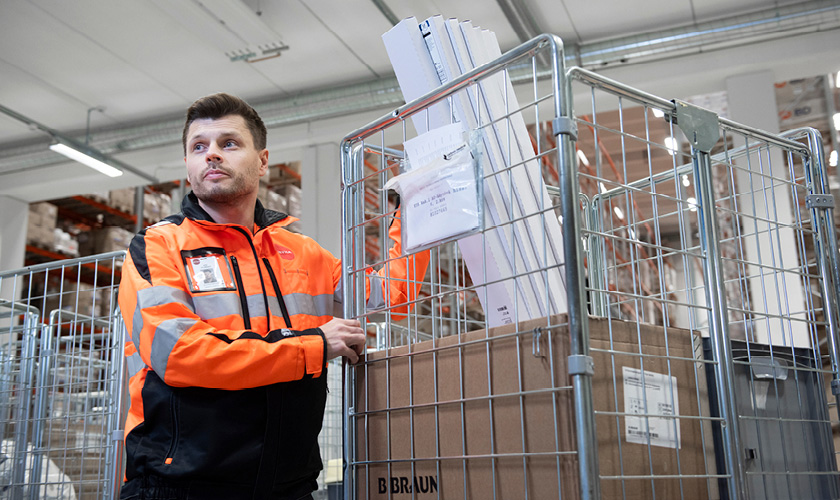 An employee of Servica's transport service pushes a warehouse trolley with boxes inside.